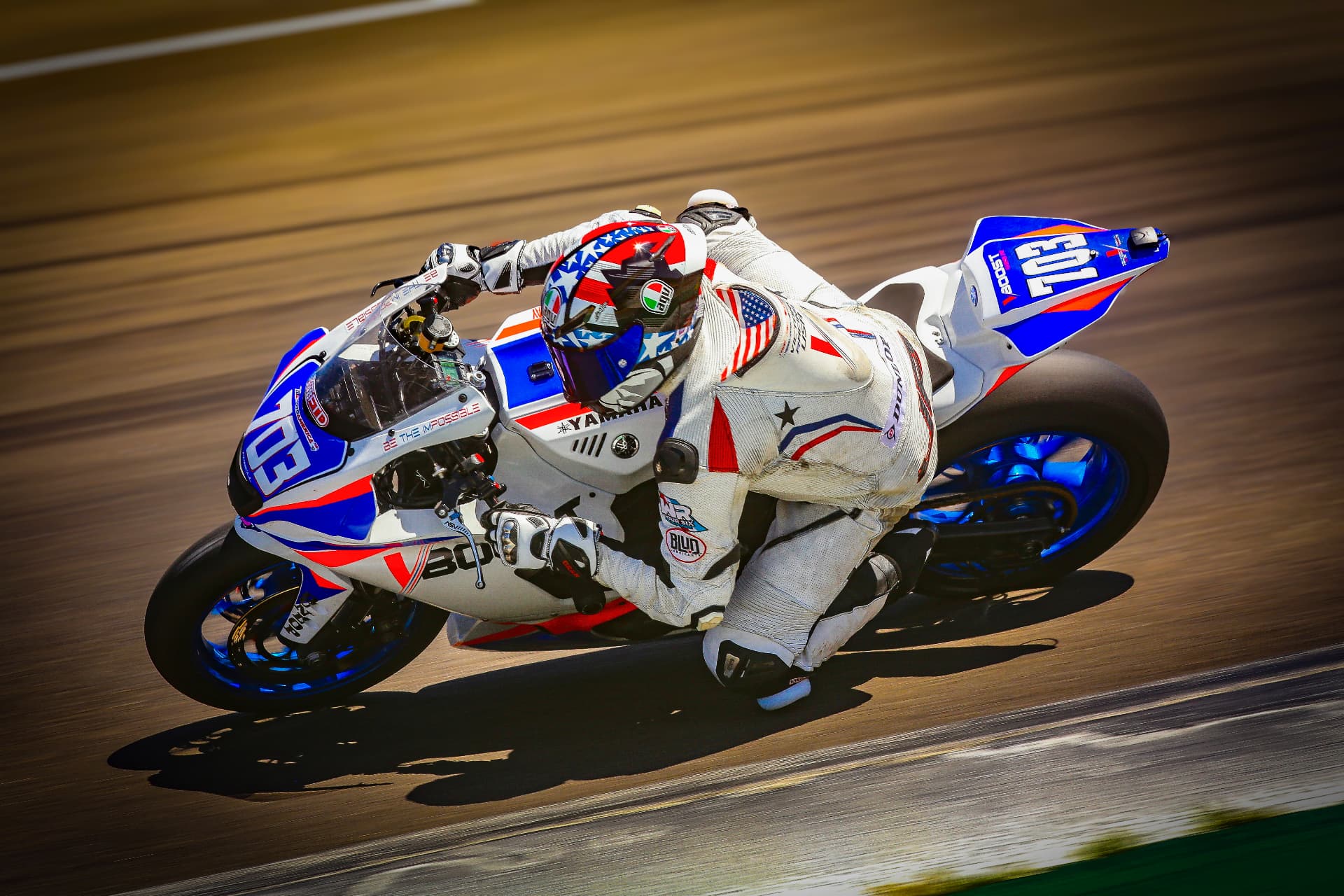 Joel Powell leaning through a corner on his #703 motorcycle at Laguna Seca