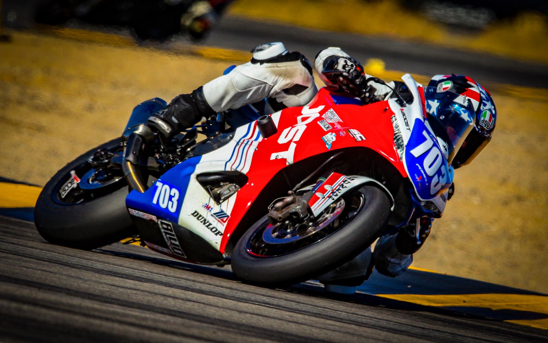 Joel Powell cornering at Chuckwalla on his red, white and blue #703 motorcycle